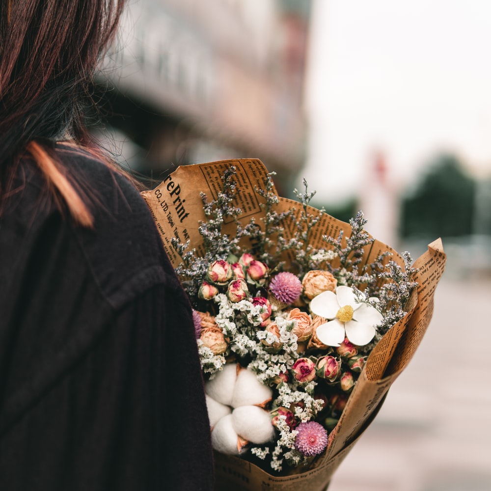 Woman In Black Coat Holding Brown Basket With White And Red Round Fruits