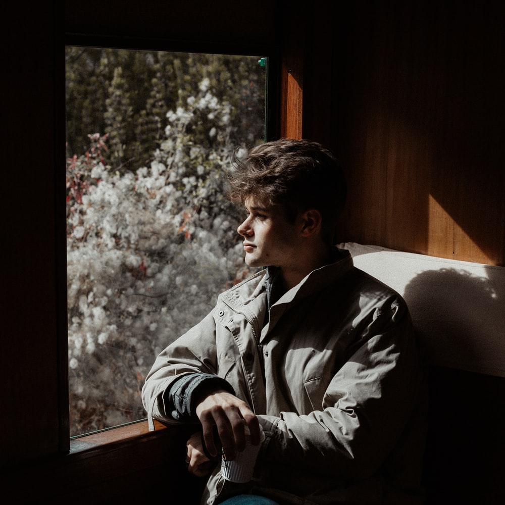 Man In Gray Jacket Sitting On Window