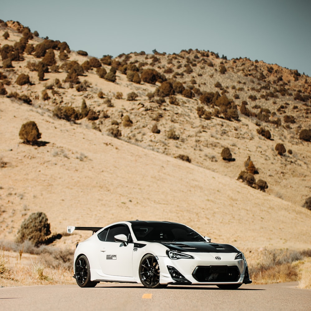 White And Black Porsche 911 On Brown Sand raster image