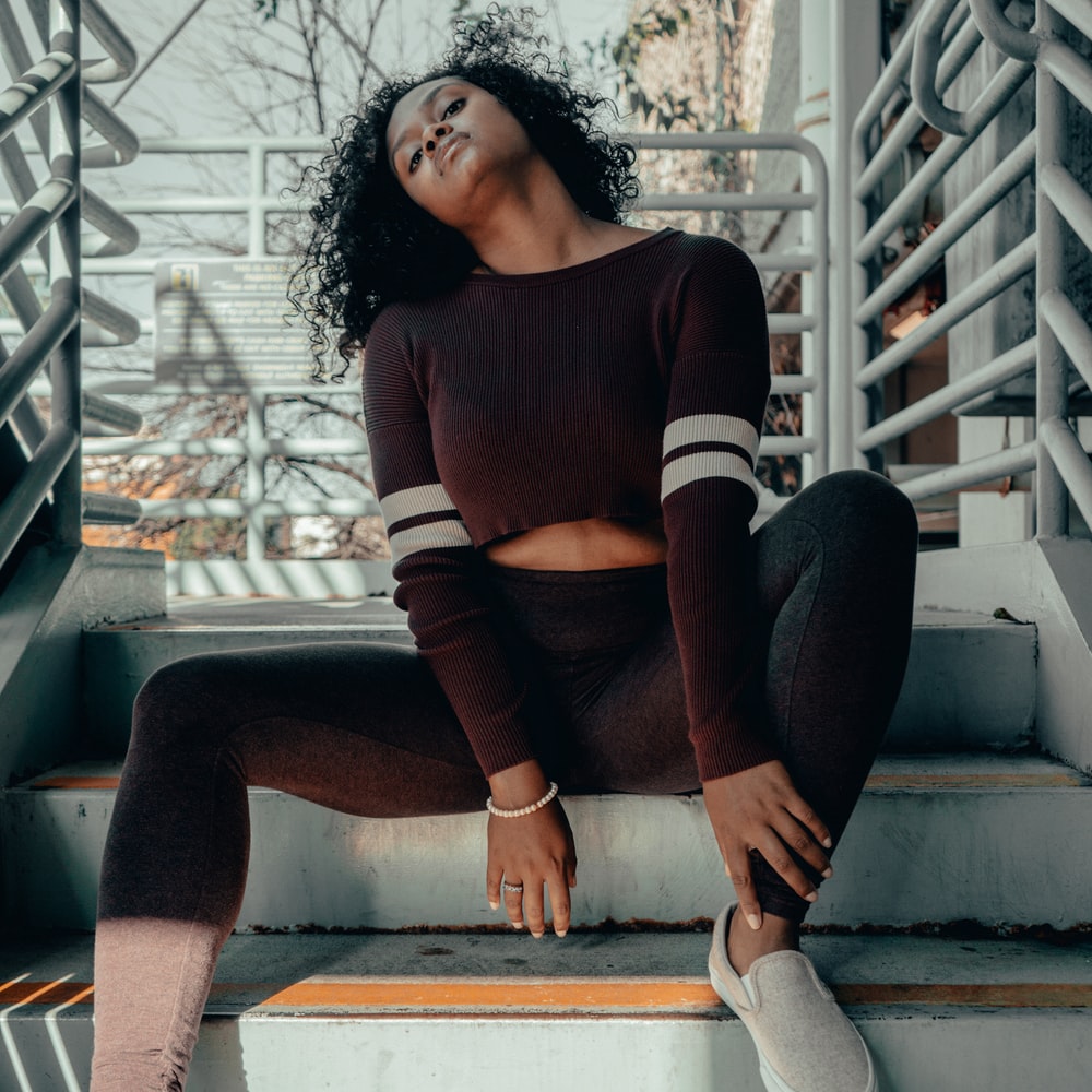 Woman In Red And White Long Sleeve Shirt And Black Pants Sitting On White Concrete Staircase