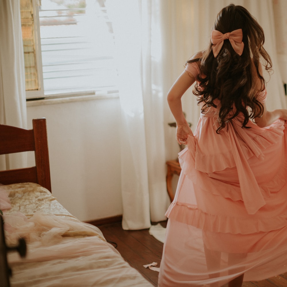 Woman In Pink Dress Standing On Bed