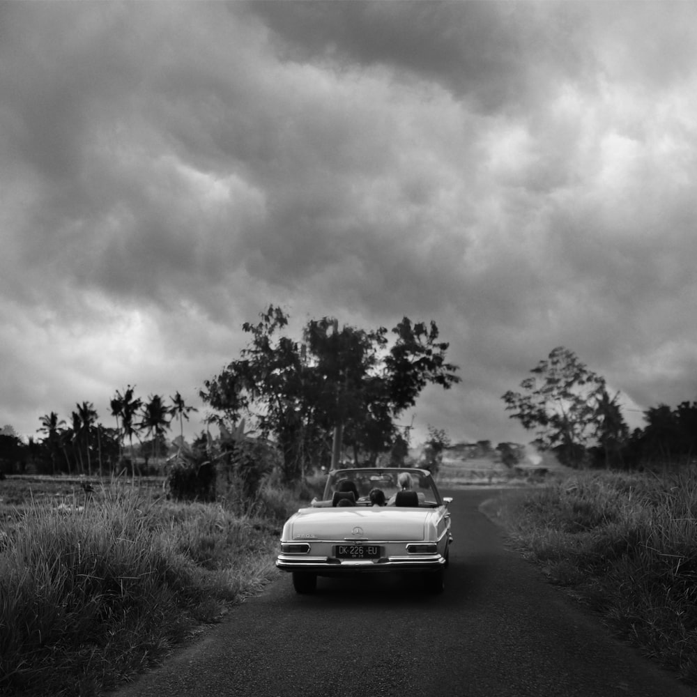 Grayscale Photo Of Car On Road raster image