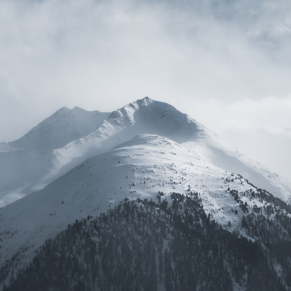 Snow Covered Mountain Under White Clouds During Daytime