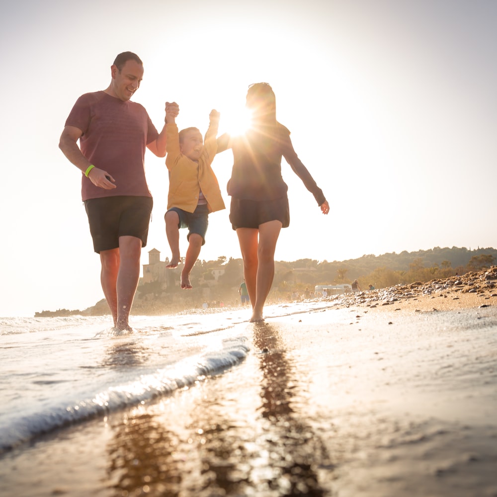 2 Men And Woman Walking On Beach During Daytime