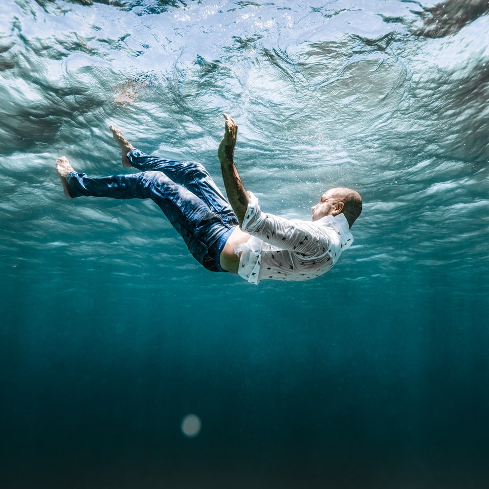 Man In White Shirt And Blue Denim Jeans Floating On Water