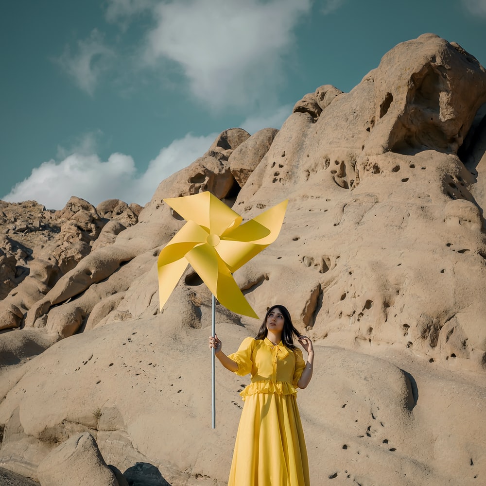 Woman In Yellow Dress Standing On White Sand During Daytime