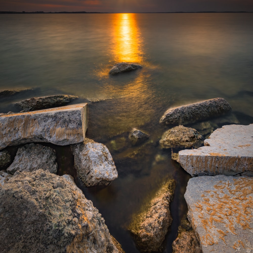 Gray Rocks On Sea During Sunset