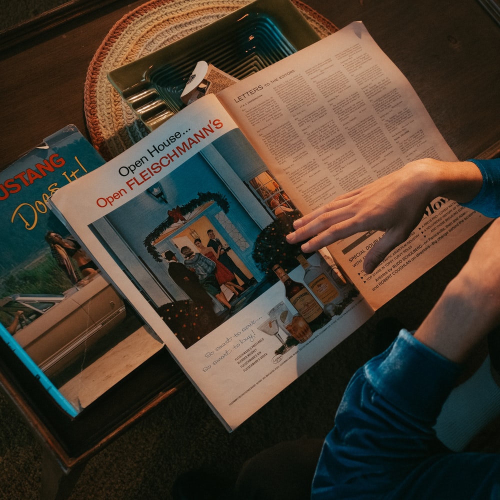 Person In Blue Long Sleeve Shirt Holding Newspaper