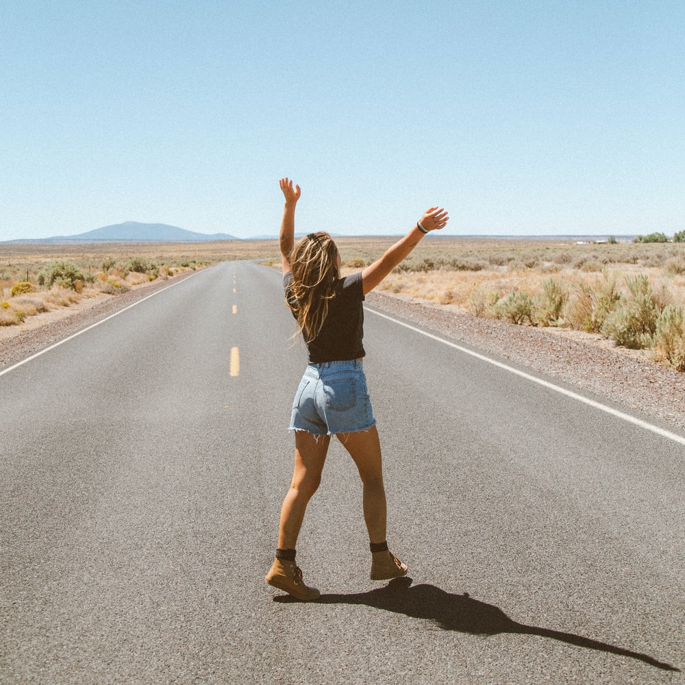 Woman In Black Tank Top And Blue Denim Shorts Running On Road During Daytime