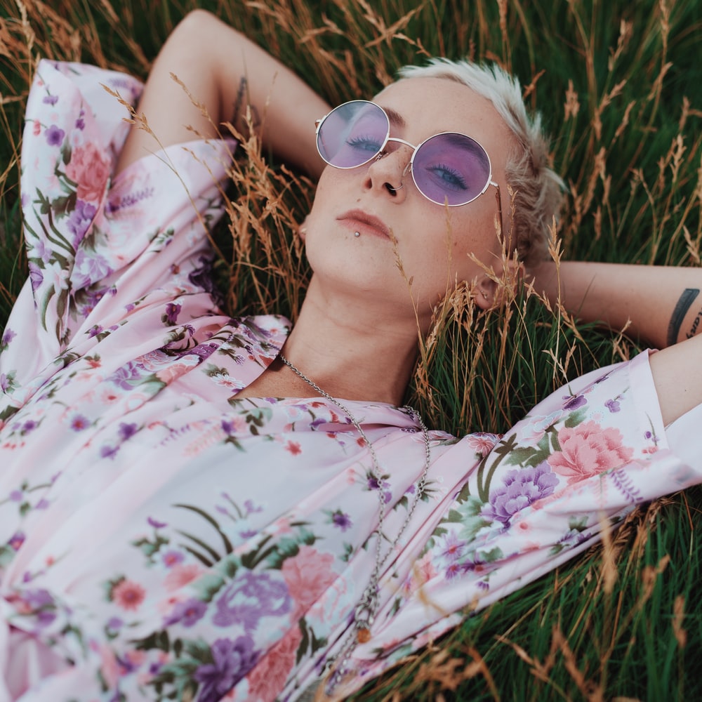 Woman In White Floral Dress Lying On Grass Field