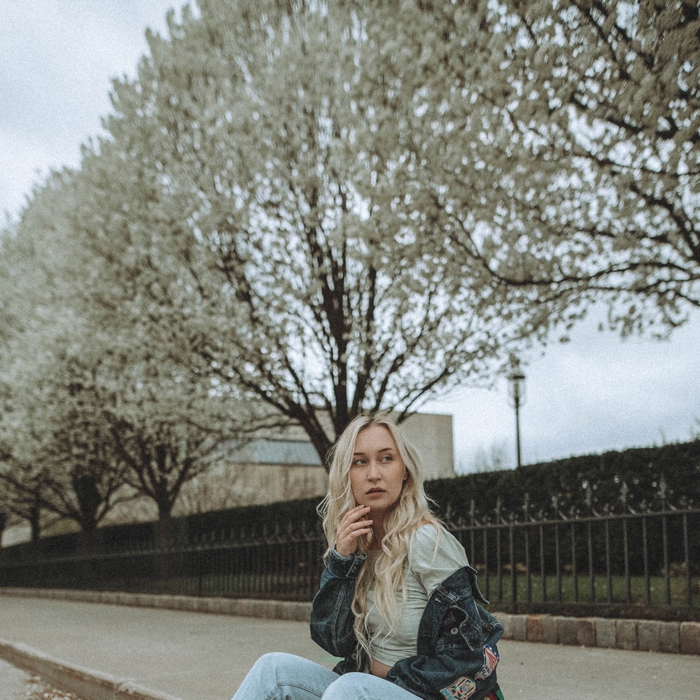 Woman In Blue Denim Jeans Sitting On Concrete Bench