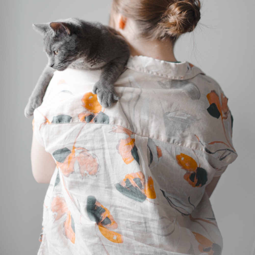 Girl In White And Orange Floral Dress Hugging Gray Cat