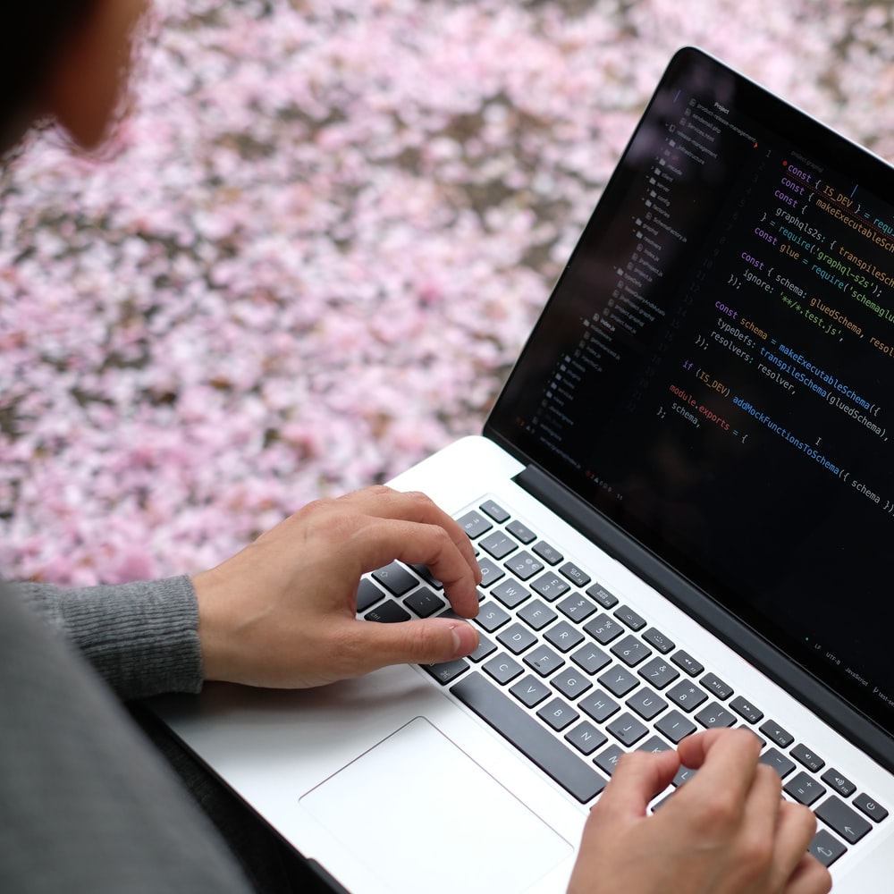 Person Using Macbook Pro On Pink And White Floral Textile
