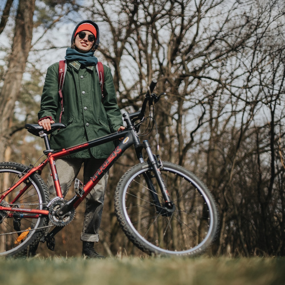Man In Green Jacket Riding On Red And Black Mountain Bike raster image
