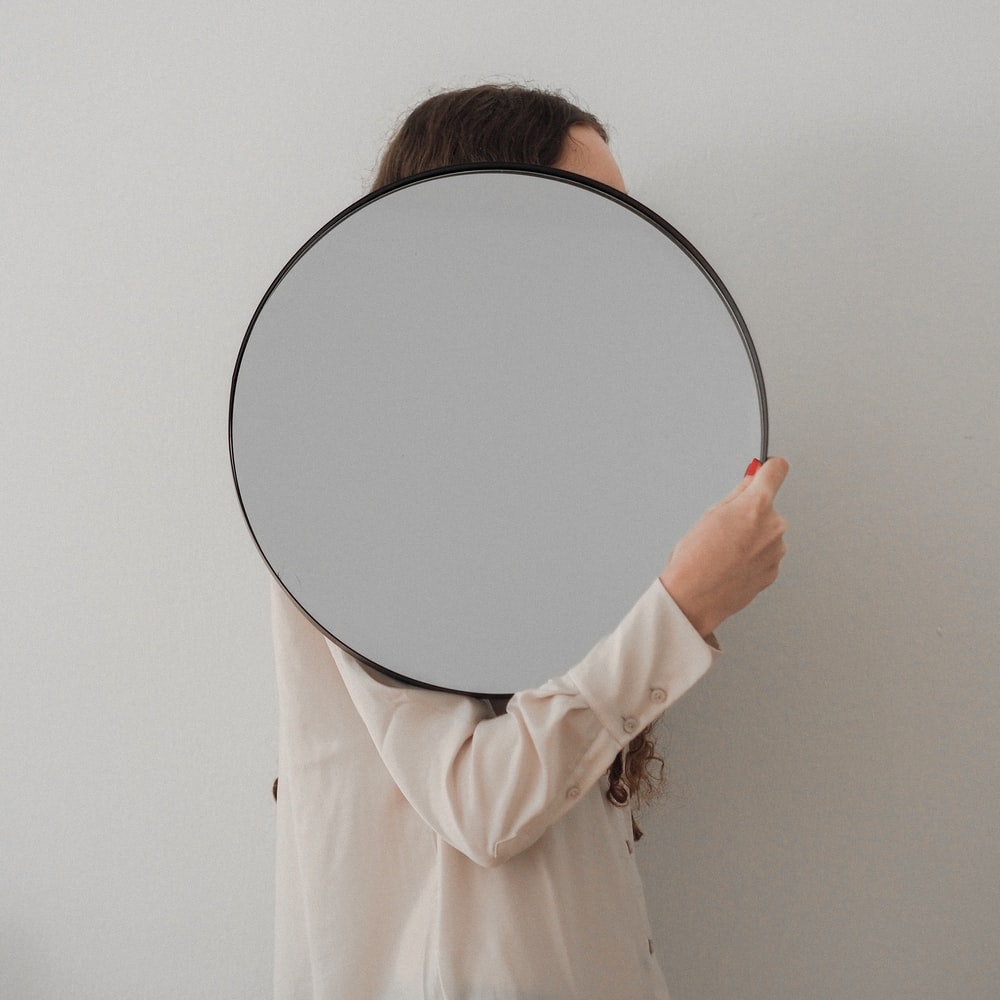 Person Holding Round Mirror With White Frame raster image