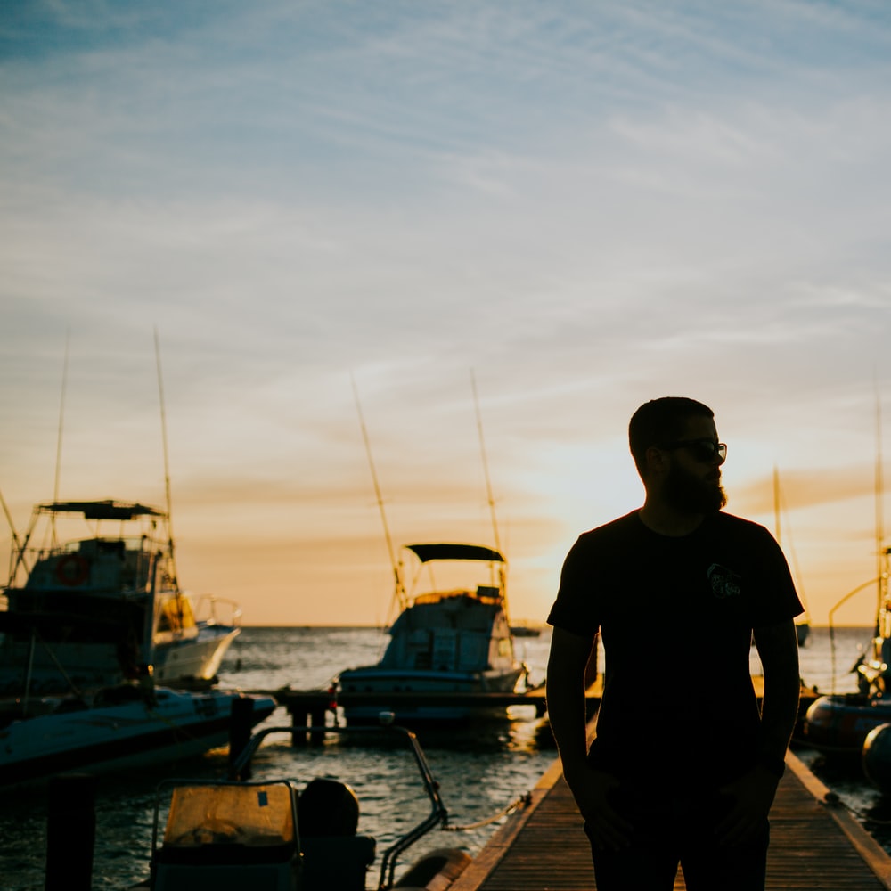 Man In Black Crew Neck T-Shirt Standing On Dock During Daytime raster image