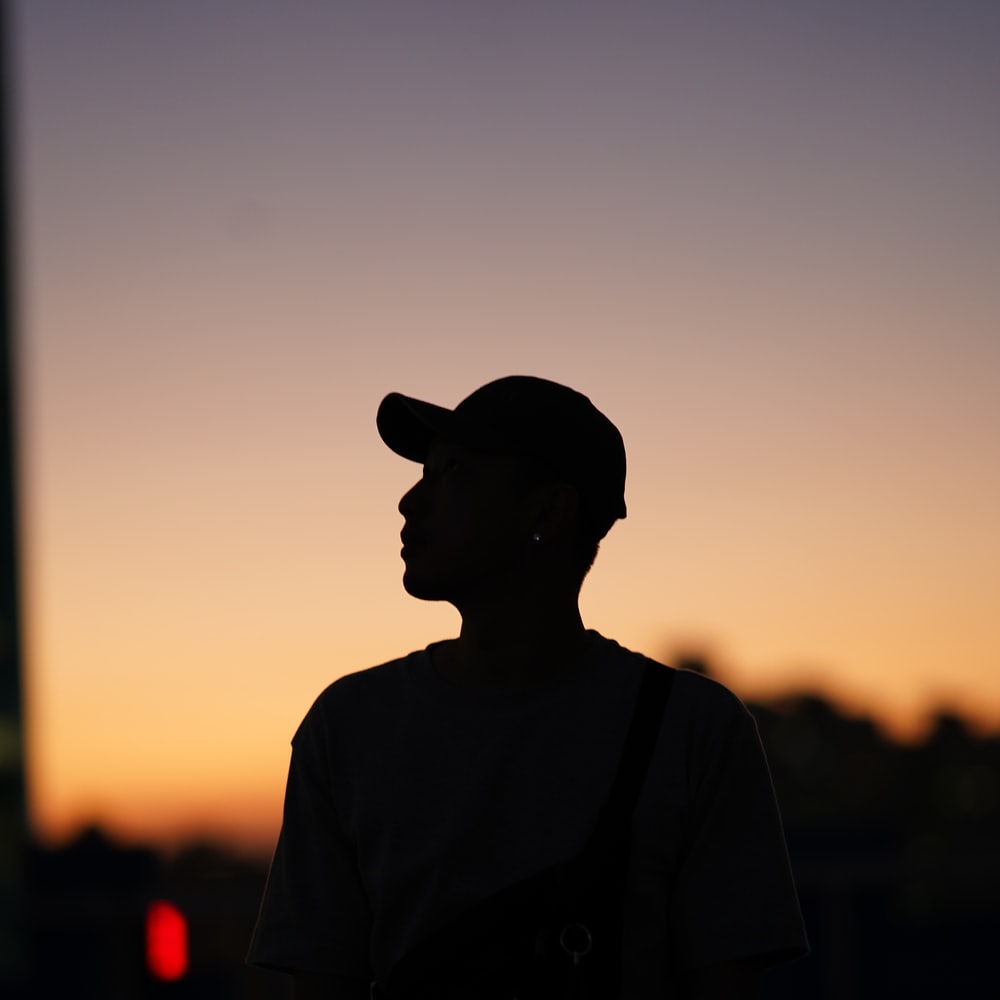 Man In Black Hat And Brown Shirt Standing On Road During Sunset