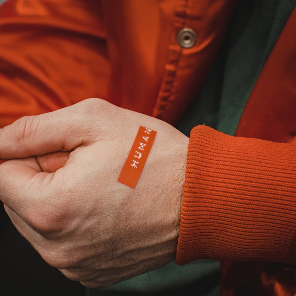 Orange And White Textile On Persons Hand raster image