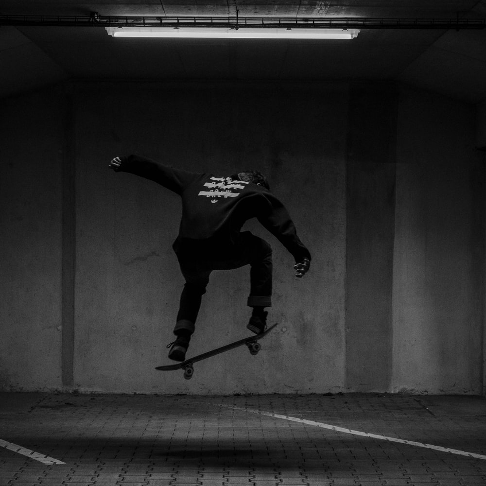 Man In Black And White Long Sleeve Shirt And Black Pants Jumping On Gray Concrete Floor