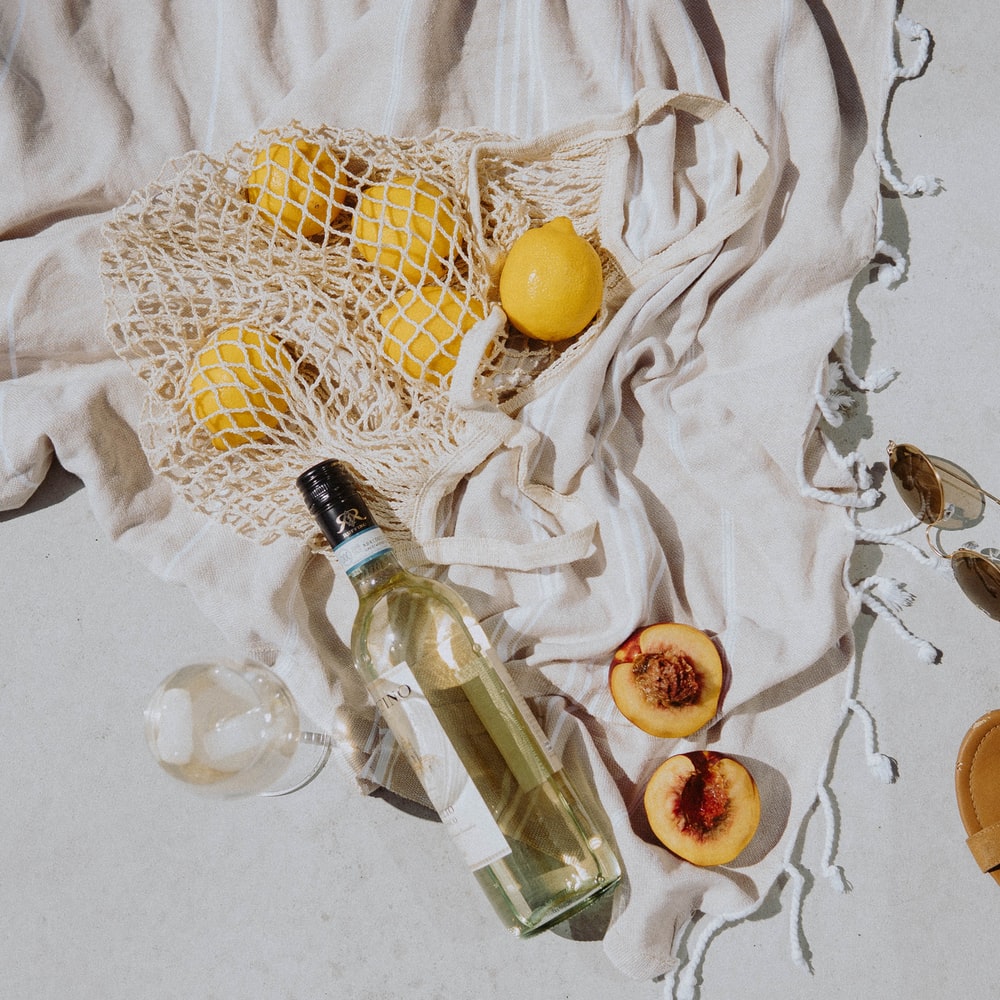Clear Glass Bottle With Yellow Round Fruit On White Textile