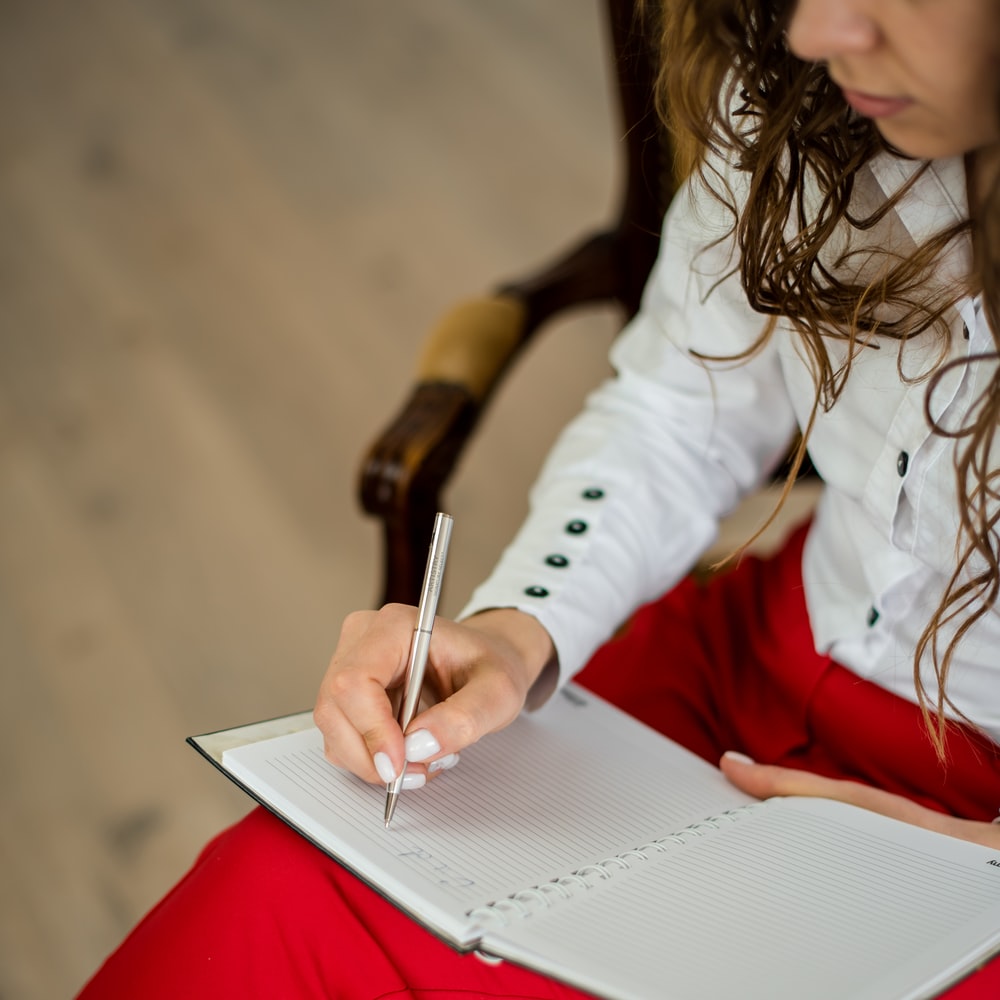Woman In White Long Sleeve Shirt Writing On White Paper raster image
